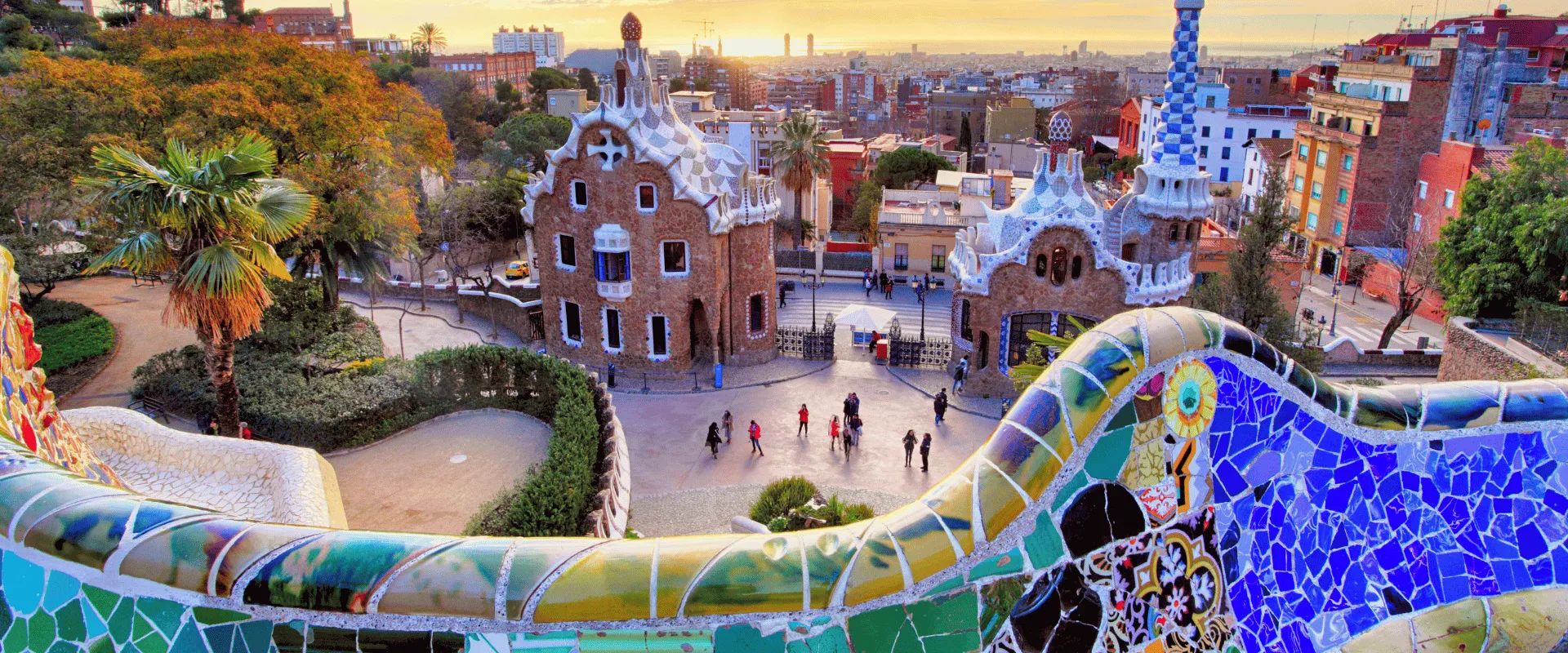 View from the mosaic serpentine bench on Nature Square over the entrance pavilions of Park Güell and Barcelona