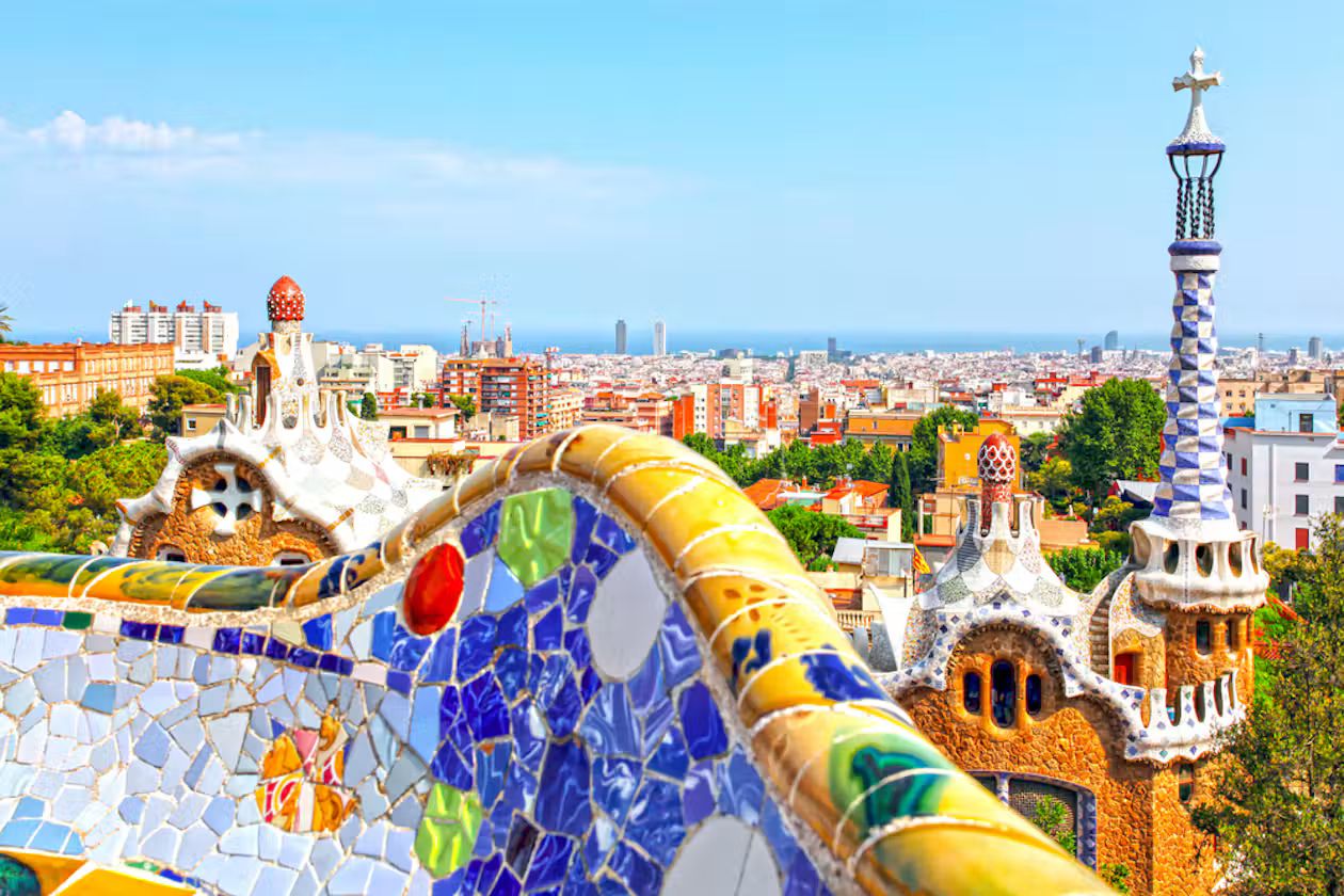 Mosaic serpentine bench on Nature Square with an entrance pavilion tower and Barcelona stretching to the sea
